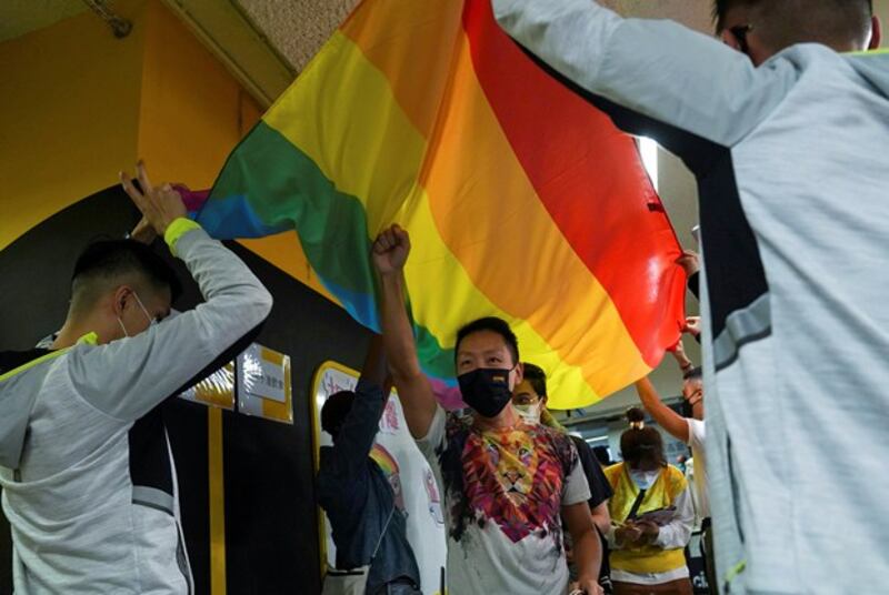 Supporters of LGBTQ rights walk under a flag at the Rainbow Market in Hong Kong following the cancellation of the annual pride parade for the second year in a row due to the COVID-19 pandemic, Nov. 13, 2021. (Lam Yik/Reuters)