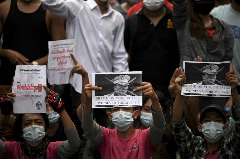 Protesters hold placards during a demonstration against the military coup in Yangon, Feb. 6, 2021. Credit: AFP