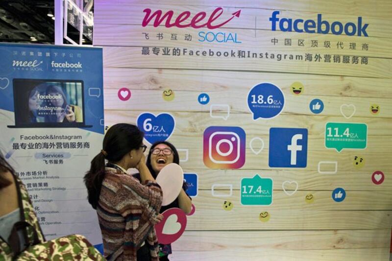 A woman reacts near a booth promoting overseas marketing services on Facebook and Instagram, which are banned in China, during an internet conference in Beijing in 2017. (Ng Han Guan/AP)