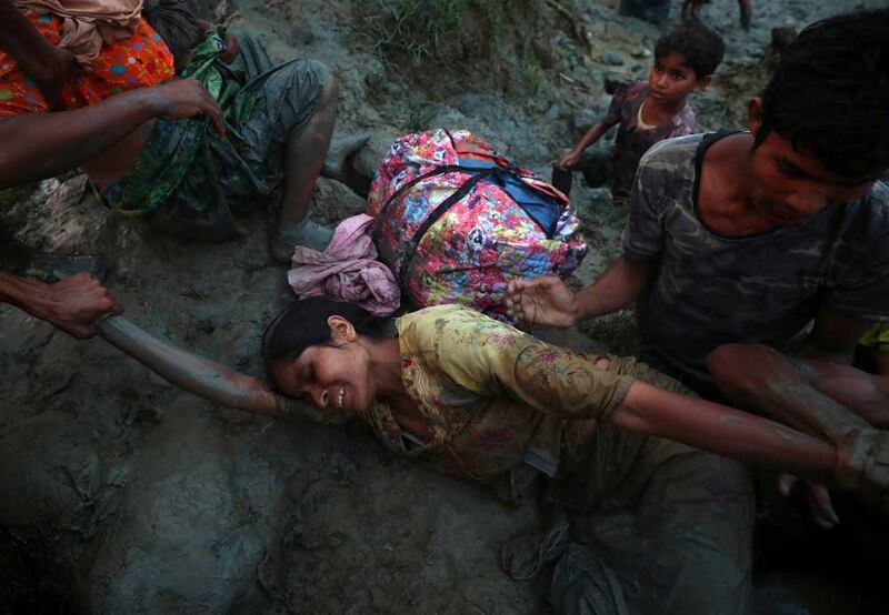 A Rohingya refugee woman is helped out of Naf River as they cross the Myanmar-Bangladesh border in Palong Khali, near Cox's Bazar, Bangladesh, November 1, 2017. REUTERS/Hannah McKay