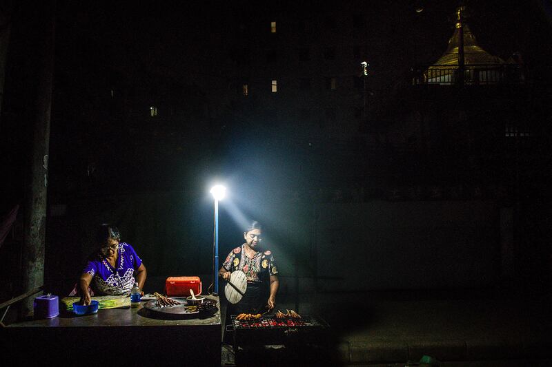 Vendors wait for customers at their roadside food stall during an electricity blackout in Yangon on April 26, 2024.