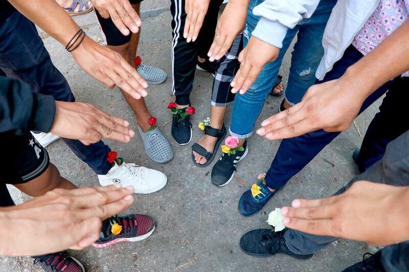 A group of protesters shows the three-fingered symbol of resistance and wear flowers in their shoes as they gather in Yangon. They later walked through the markets and streets of Kamayut township to show their resistance to coup. (Associated Press)