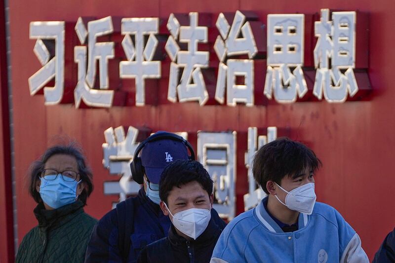 路人站在习近平法治思想学习园地前；中共加强对教育的控制，要求学校反对和抵制西方宪政，三权鼎立等“错误观点”。（美联社）