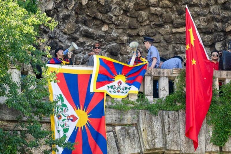 Tibetan protesters displayed Tibetan flags next to Chinese national flags on Gellert Hill to oppose Chinese President Xi Jinping's visit to Budapest, Hungary, May 9, 2024. (Denes Erdos/AP)