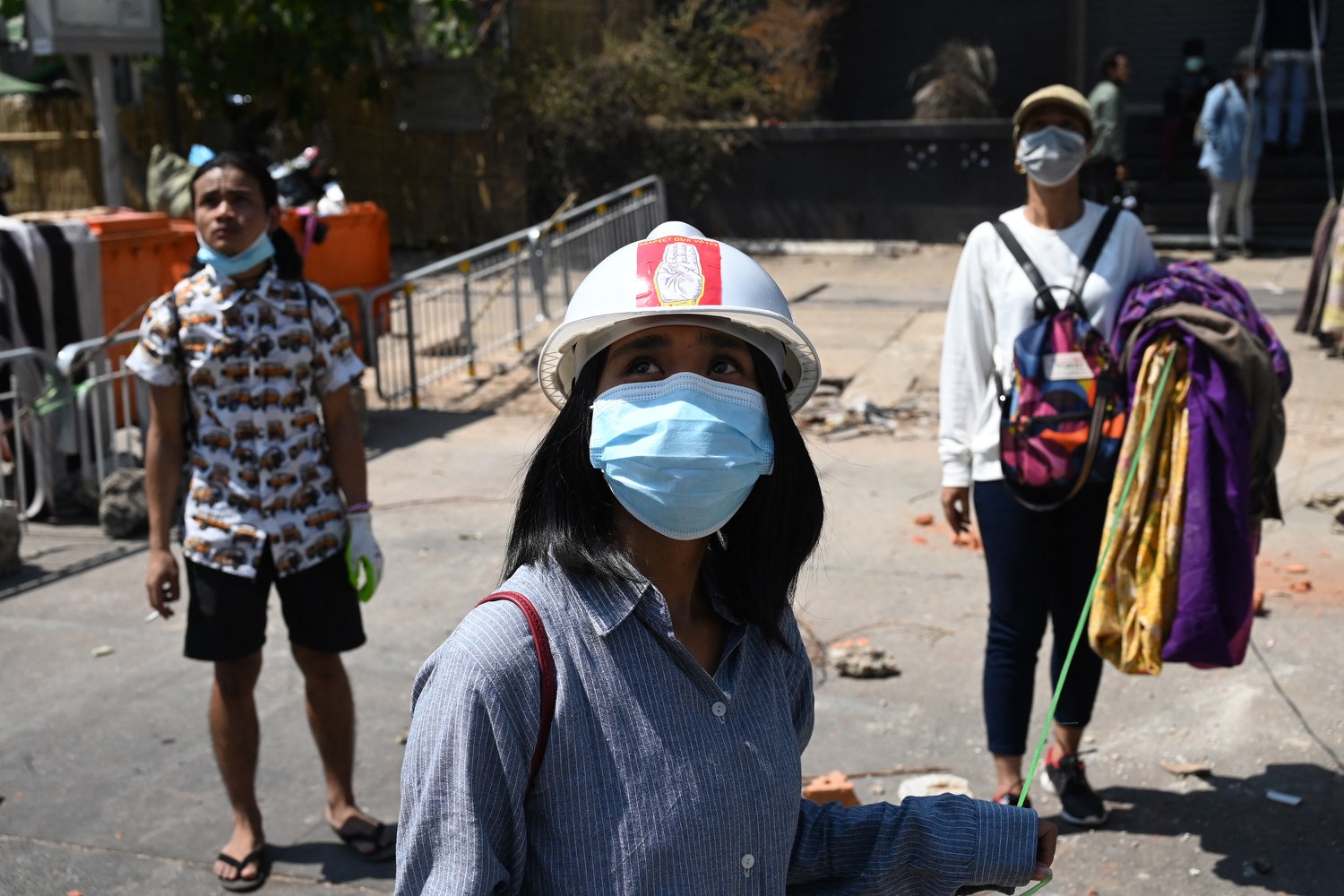 Women hang a collection of longyi, a traditional clothing widely worn in Myanmar, across a road during a demonstration against the military coup in Yangon on March 8, 2021. Because walking beneath them is traditionally considered bad luck for men, the lines of clothing are meant to slow down police and soldiers. Credit: AFP