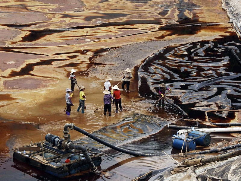 Workers drain away polluted water near the Zijin copper mine in Shanghang,  China, July 13, 2010.