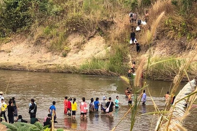 Civilians fleeing fighting between the Myanmar military and the Karen National Union cross a river in eastern Myanmar's Kayin state, along the Thai-Myanmar border, Dec. 25, 2021. Credit: AFP