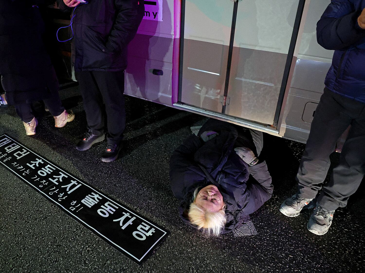 A woman lies on a road to block a vehicle transporting an army unit, after South Korean President Yoon Suk Yeol declared martial law, in Seoul, Dec. 4, 2024.