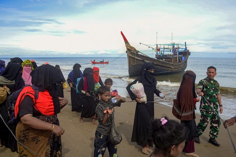 Rohingya migrants are escorted after their boat carrying 119 people landed on the coast of Bluka Teubai, North Aceh, Indonesia, on November 16, 2022, after surviving a five week journey at sea. Credit: AFP