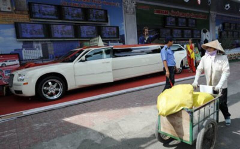 Một người dân lao động nghèo đẩy xe hàng rong qua một cửa hàng bán kim khí điện máy ở Saigon. AFP photo