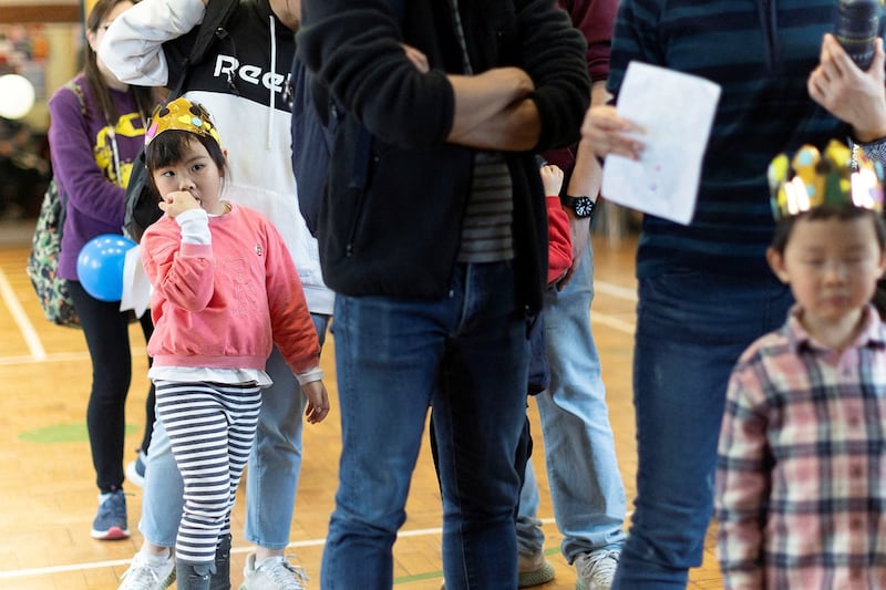 People line up at the Coronation Children's Fair organized to encourage newcomers from Hong Kong families to celebrate with the local community, at Trinity Church, in Sutton, London, April 29, 2023. (May James/Reuters)