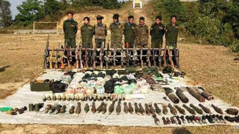 The eight Myanmar militiamen captured by the Ta'ang National Liberation Army stand behind arms and bags of drugs seized at their camps in Myanmar's northern Shan state, March 15, 2020.