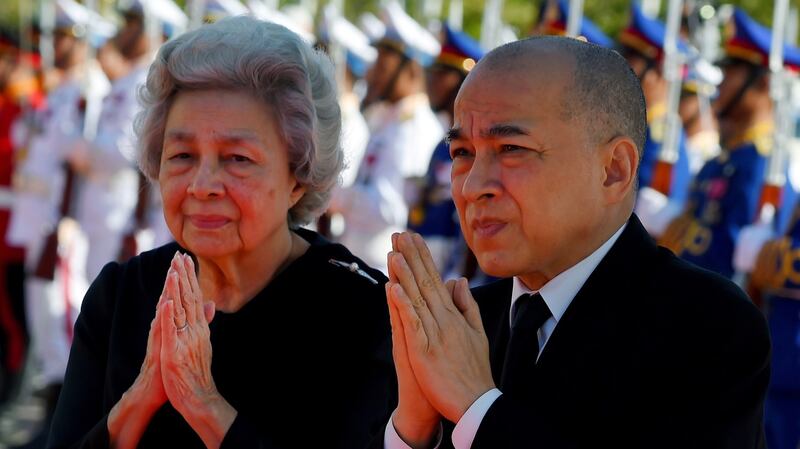 Cambodia's King Norodom Sihamoni (R) and his mother former queen Monique (L) walk past honor guards during the cremation of Princess Norodom Buppha Devi in front of a pagoda in Phnom Penh, Nov. 25, 2019.