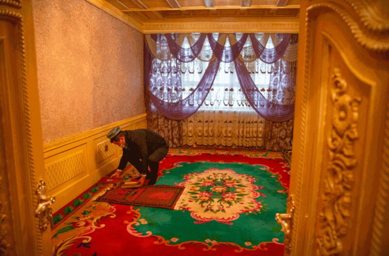 Tursunjan Mamat sets down a copy of the Quran during a government organized visit for foreign journalists to his home in Aksu prefecture, northwestern China's Xinjiang Uyghur Autonomous Region, April 20, 2021. Credit: Associated Press