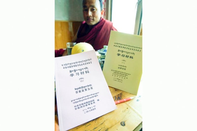 A Tibetan Buddhist monk holds two Chinese government textbooks on religious policies and laws and regulations given to monks at a monastery near Xiahe in China's Gansu province, May 8, 2008. (Ng Han Guan/AP)