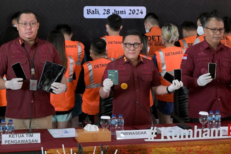 Indonesian immigration officials show passports and mobile devices seized while Taiwanese citizens arrested during a cybersecurity investigation are presented at a news conference in Bali, June 28, 2024. (Sonny Tumbelaka/AFP)