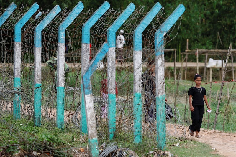 A Rohingya refugee walks past a camp border fence in Cox's Bazar, Bangladesh, Sept. 28, 2024.