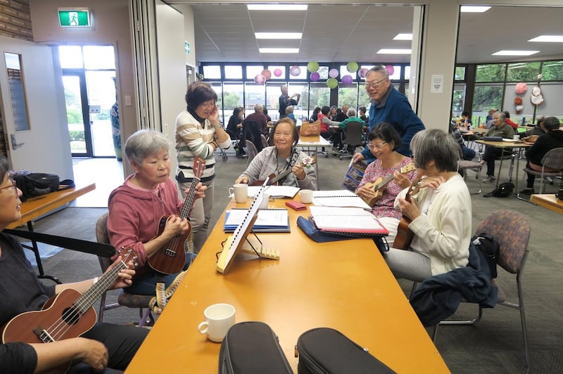 Chinese-New Zealanders sing and play ukuleles at the Auckland Chinese Community Center, where immigrants from China and other Asian countries socialize, play music, and square off at mahjong or chess. Credit: RFA.