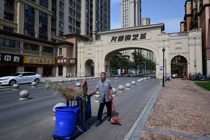 2023年6月20日，一名环卫工人站在河南省郑州市新郑市一栋未完工公寓楼入口前。（法新社）