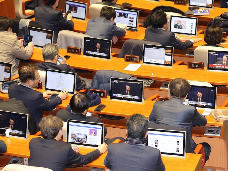 South Korean lawmakers watch screens showing a news broadcast of President Yoon Suk Yeol's speech on lifting martial law, at the main conference hall of the National Assembly in Seoul on Dec. 4, 2024.