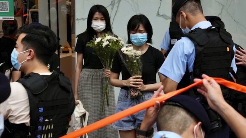 2021年7月2日，持白花悼念梁健辉的市民被警方截查。（美联社）