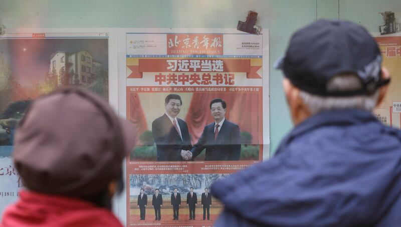 2012年11月16日，北京市民在街道上阅读一篇报道有关习近平与他的前任胡锦涛的报纸头条。（美联社）