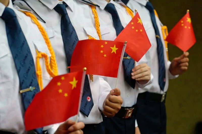 Students hold Chinese national flags during a flag raising ceremony at a school in Hong Kong, July 1, 2021. Credit: Vincent Yu/Associated Press