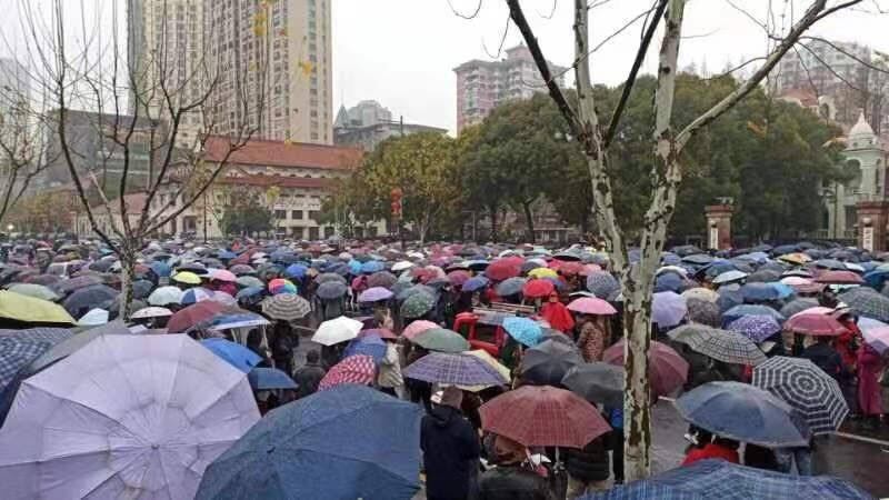 2月8日，武汉上万名退休工人在市政府门前聚集，警方人员在大巴车内戒备。（网络图片/古亭提供）