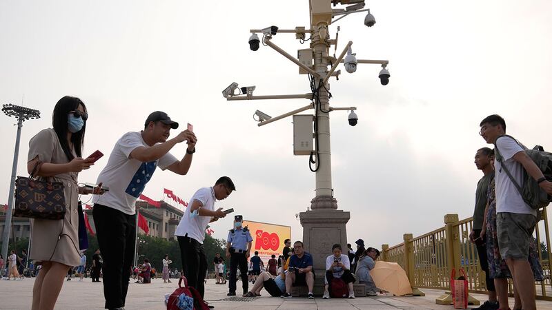 2021 年 7 月 15 日，在北京天安门广场附近，人们在监视摄像机附近拍照。（美联社）