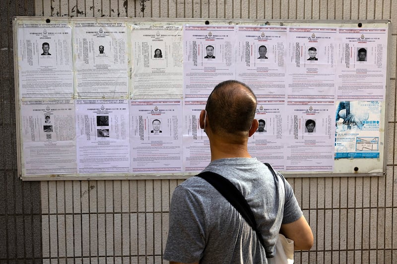 A pedestrian in Hong Kong looks at police reward notices for eight pro-democracy activists living in the United States, Britain, Canada and Australia, July 14, 2023. (AP Photo/Louise Delmotte)