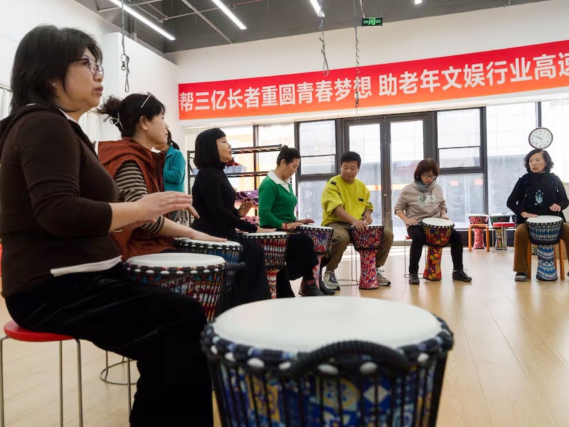 People play drums at a workshop run by the Beijing Senior University, Oct. 23, 2024.