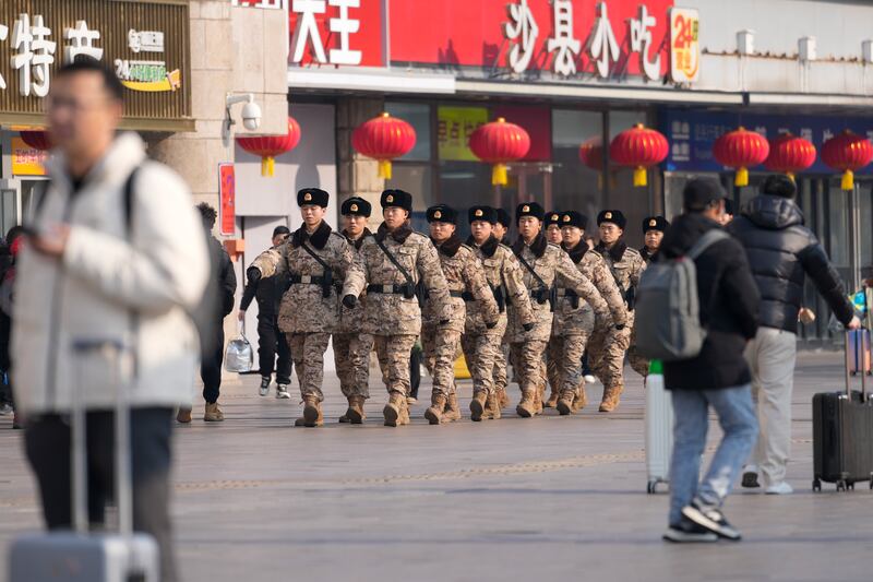 Chinese soldiers march as travelers arrive to catch their trains at the Beijing West Railway Station ahead of the Lunar New Year in Beijing,  Jan. 24, 2025.