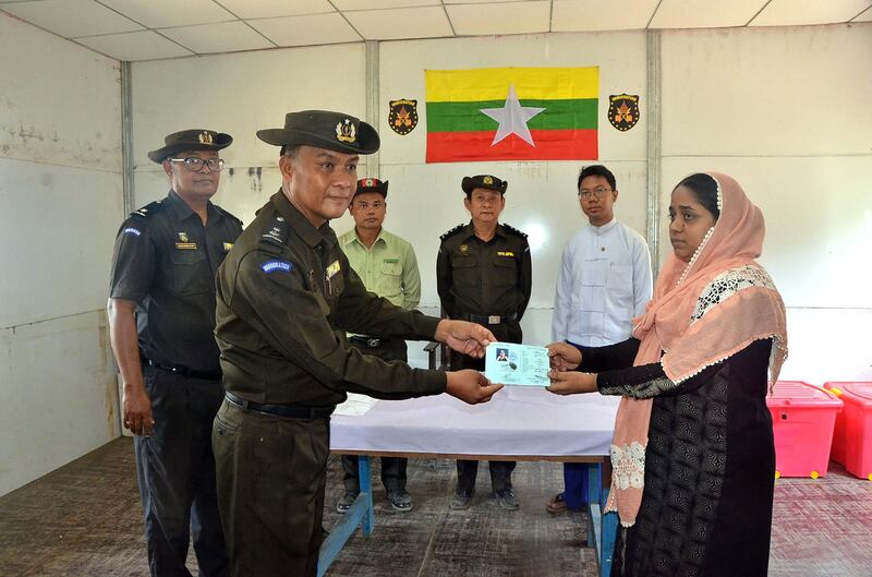 Myanmar immigration officials hand over an identification document to a Rohingya woman at the Taungpyoletwei town repatriation camp in Rakhine state's Maungdaw township, near the Bangladesh border, in a file photo. Credit: AFP