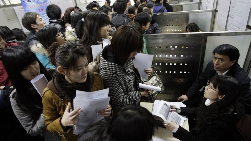 资料图片：求职者在北京的大学毕业生招聘会上排队申请职位空缺。（美联社）