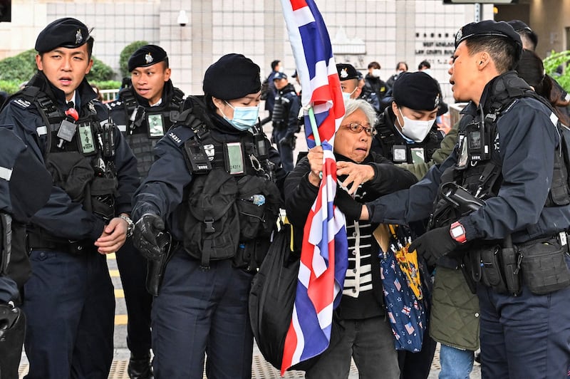 Policemen stop activist Alexandra Wong carrying Britain's Union Jack outside the West Kowloon court ahead of the trial of pro-democracy media tycoon Jimmy Lai in Hong Kong, Dec. 22, 2023. (Peter Parks/AFP)