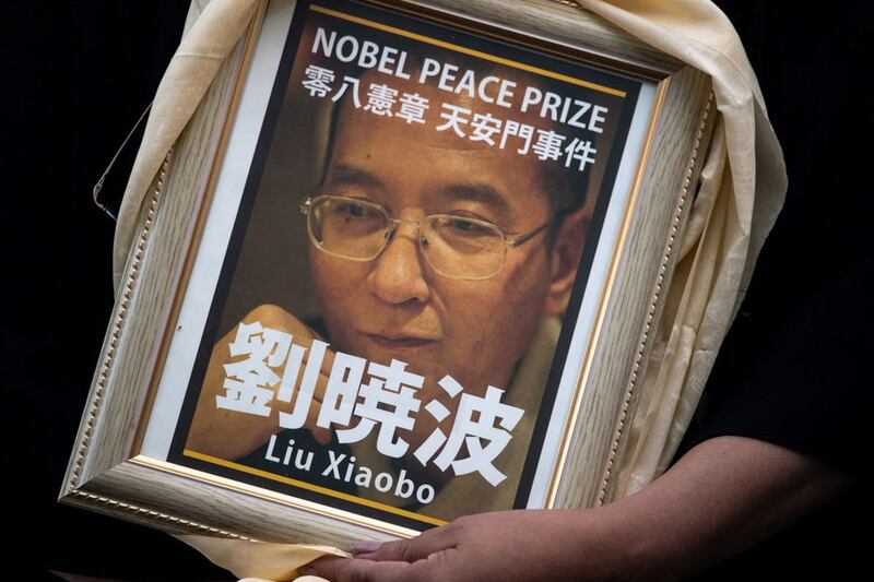 A pro-democracy activist holds a portrait of late Chinese Nobel prize winner Liu Xiaobo while attending a vigil outside a train station in Shinjuku district of Tokyo on June 4, 2022, to mark the 33rd anniversary of the 1989 Tiananmen Square crackdown in Beijing. (AFP)