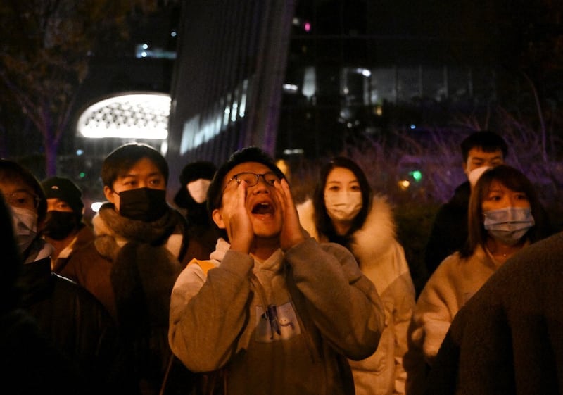 A protester shouts during a protest for the victims of a deadly fire as well as a protest against China's harsh Covid-19 restrictions in Beijing on November 28, 2022. (Photo by Noel CELIS / AFP)