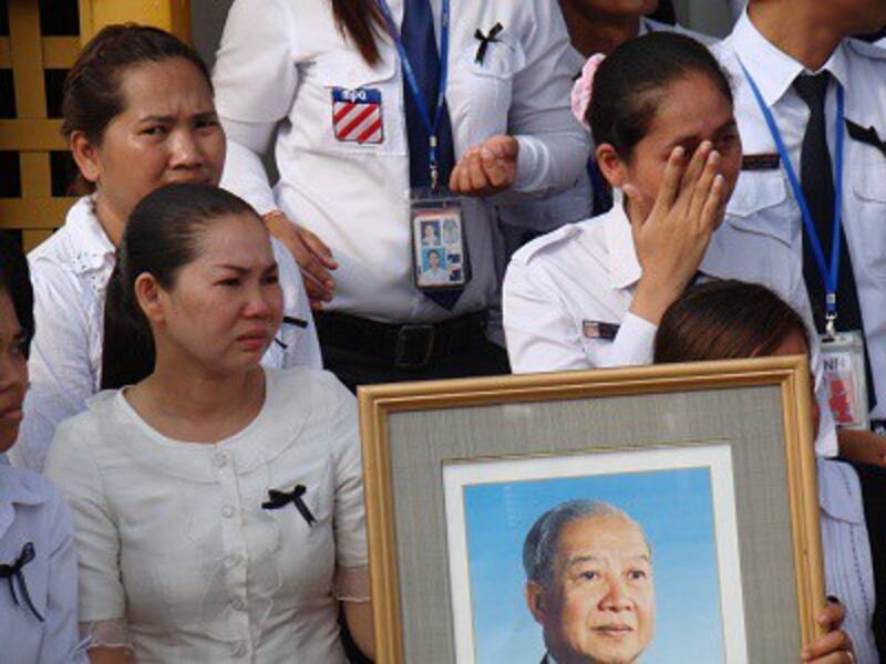 Weeping mourners hold a portrait of Sihanouk as they watch the procession of his casket from the airport in Phnom Penh, Oct. 17, 2012.