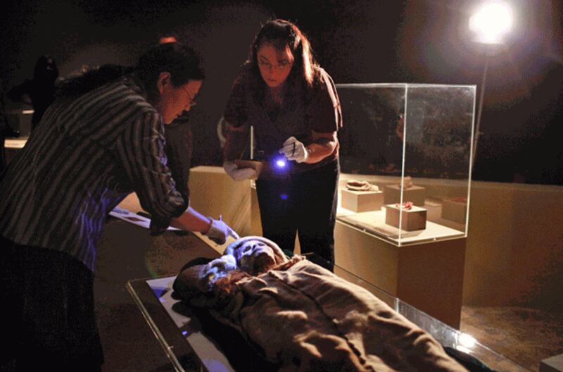 Jennifer Ring (C) and Hu Guizhen (L) examine the Beauty of Xiaohe, a 3,800-year-old mummy discovered in the Tarim Basin in northwestern China, at the 'Secrets of the Silk Road: Mystery Mummies from China' exhibit at the Bowers Museum in Santa Ana, California, March 24, 2010. Credit: Associated Press