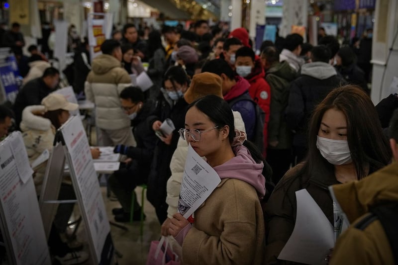 2024年2月23日，求职者在北京的招聘会上拿着宣传册寻找职位空缺。（美联社）