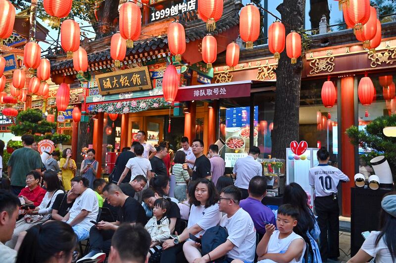 People wait outside under red lanterns for their turn to dine at a restaurant in Beijin, July 13, 2024. (Adek Berry/AFP)