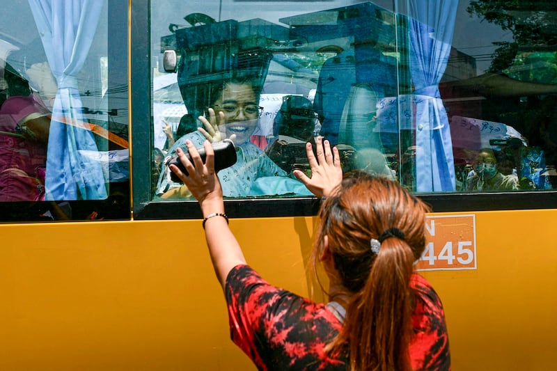 A woman touches a bus carrying prisoners being released from Insein prison for the Buddhist New Year, in Yangon on April 17, 2024. (AFP)