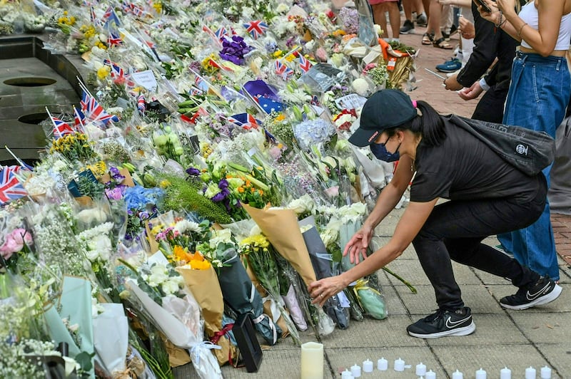 People lay flowers as a tribute to Queen Elizabeth II outside the British Consulate in Hong Kong, Sept. 12, 2022. Credit: AFP