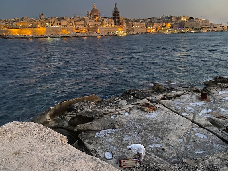 A man prays on a rock at Fort Tigne in front of Valleta, in Sliema, the northeast coast of Malta, June 18, 2022. Ing was hoping to become a citizen of Malta, another EU member state whose border is lapped on all sides by the waves of the Mediterranean. (REUTERS/Nacho Doce)