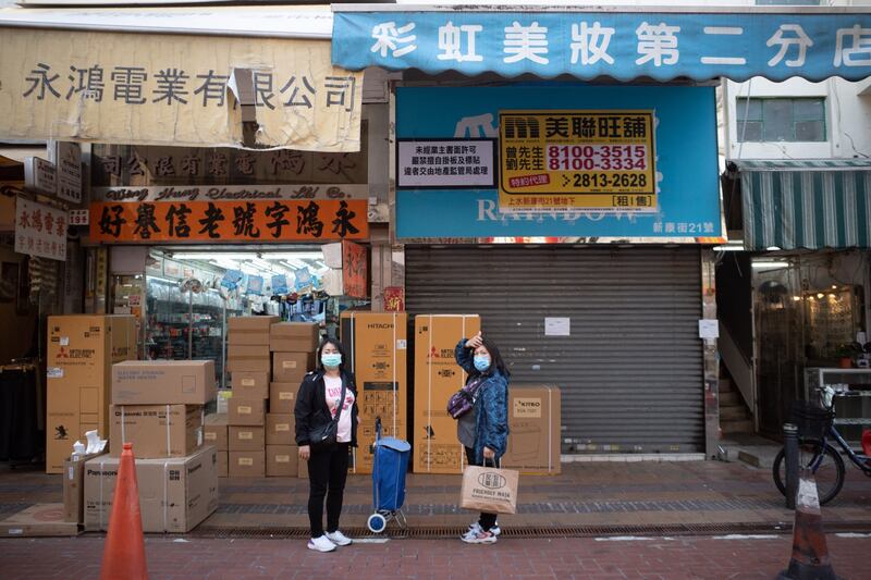 People stand in front of an empty shop lot for rent in Hong Kong, Dec. 10, 2021. (Bertha Wang/AFP)