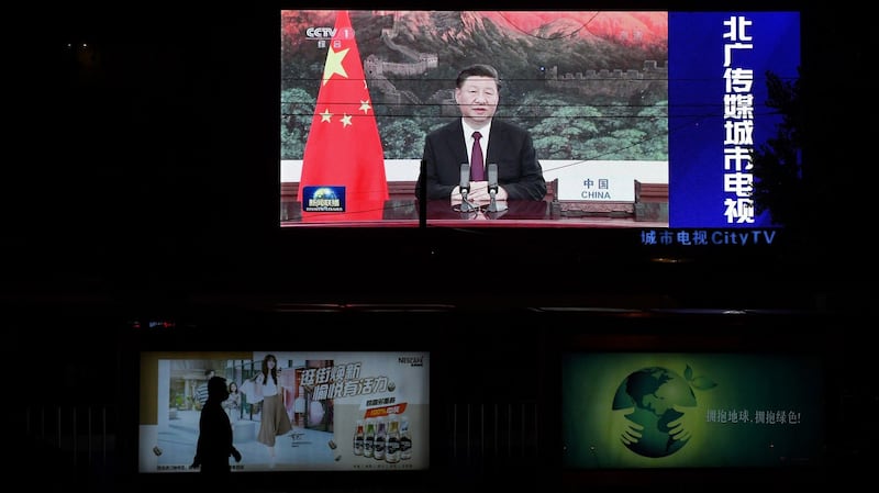 An image of Chinese President Xi Jinping appearing by video link at the United Nations 75th anniversary is seen on an outdoor screen as a pedestrian walks past below in Beijing, Sept. 22, 2020.