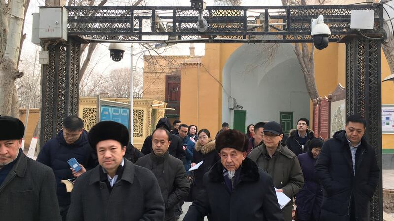 Imams and government officials pass under security cameras as they leave the Id Kah Mosque during a government-organized trip in Kashgar, XUAR, Jan. 4, 2019. Reuters