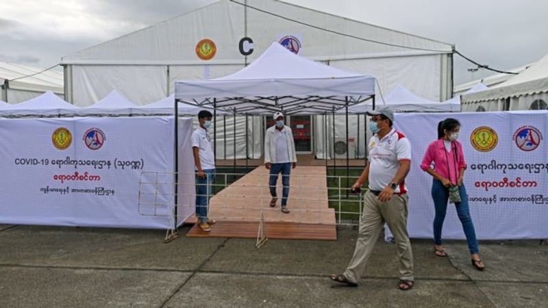 Volunteers walk by a new temporary shelter for COVID-19 patients built on a soccer field in Myanmar's commercial hub Yangon, Sept. 19, 2020.