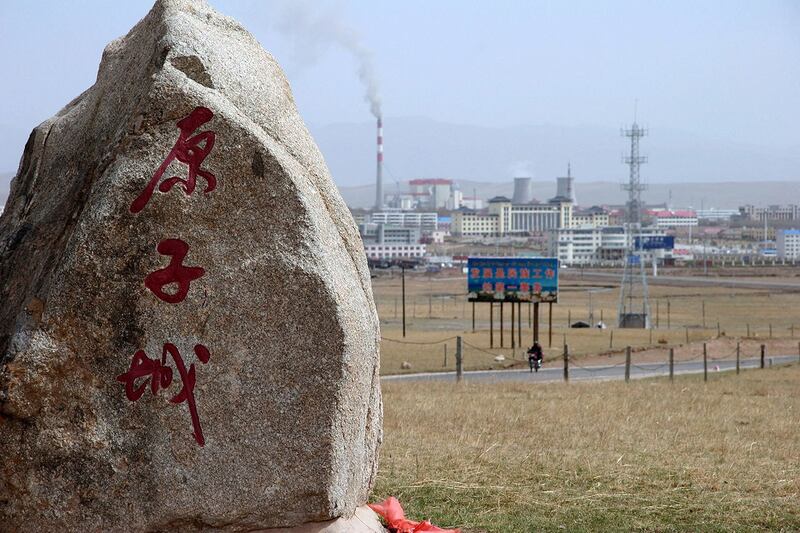 2007 年 5 月 12 日，中国青海省海盐市，在通往中国第一个核武器基地的道路上，一块纪念碑石标志着“核城”，背景是一座新的工业城市，该基地已解密并向游客开放。（法新社）