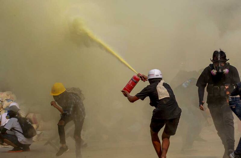 As security forces approach, a protester uses a fire extinguisher to provide cover Wednesday in Yangon.